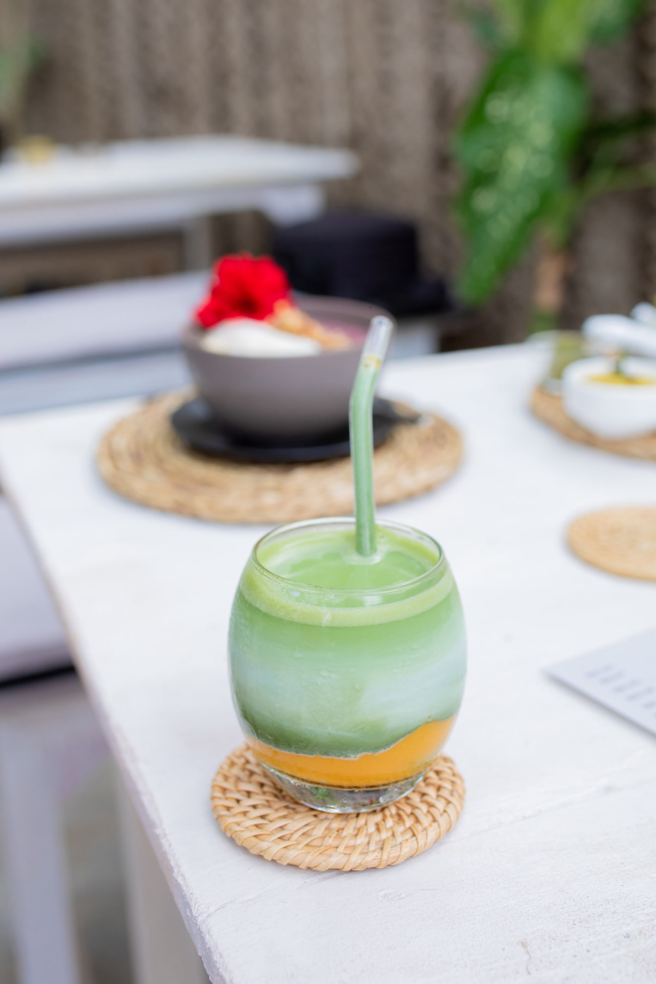 Layered matcha drink in a glass with a glass straw